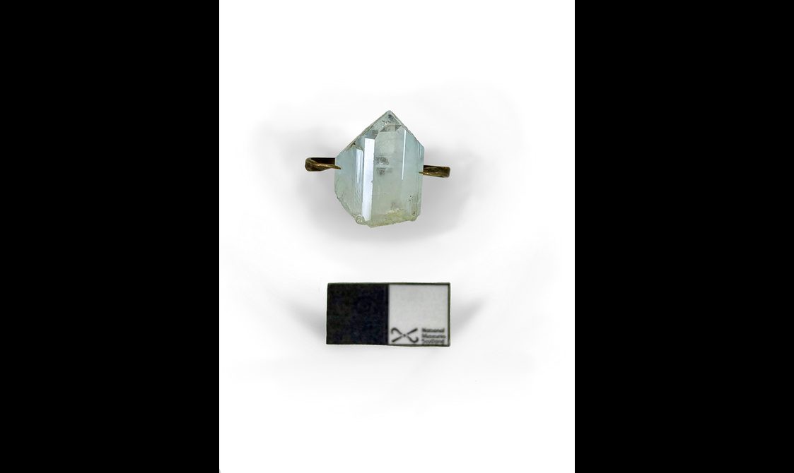 A clear blue gem on a strip of brass