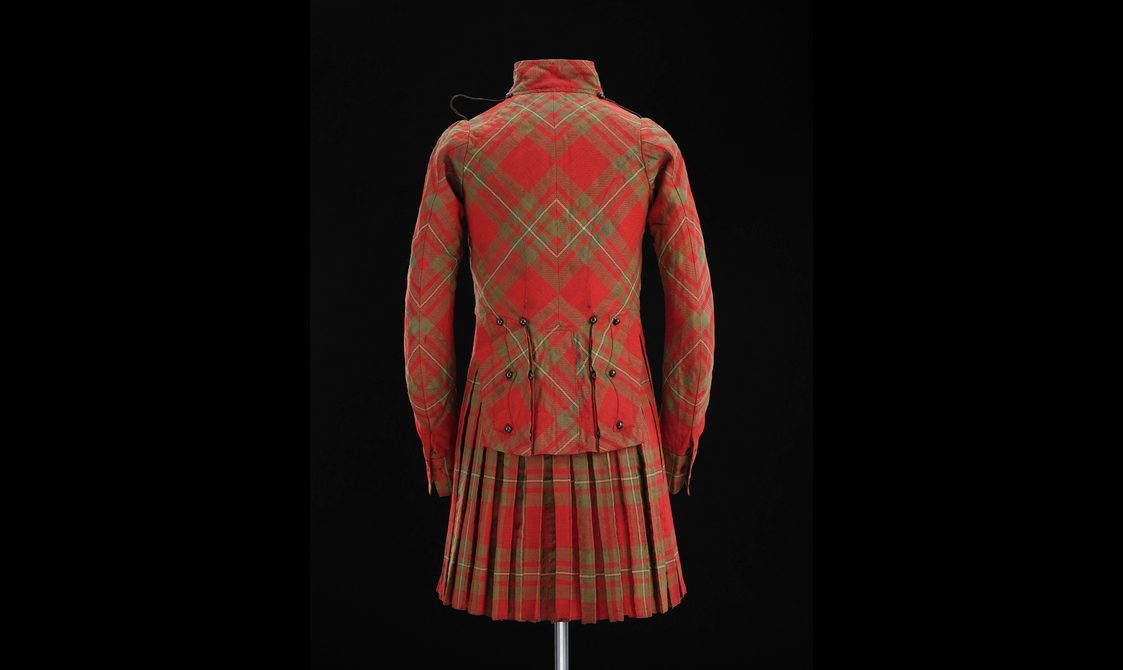 Back of a mannequin wearing a red tartan kilt with a matching jacket.
