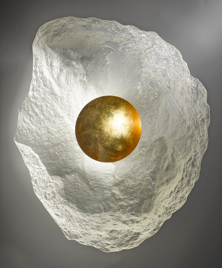 Irregularly shaped oval glass form. Mostly translucent, but with a round gold central well.