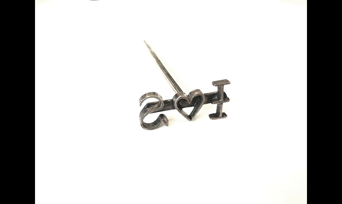 A T shaped pin like metal branding tool with reverse text I heart symbol S
