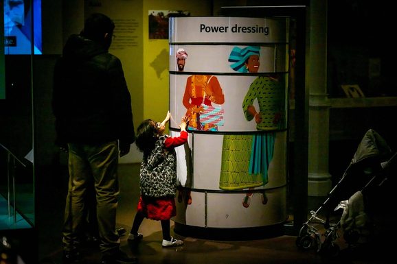 A child interacting with a dressing game in a museum gallery.
