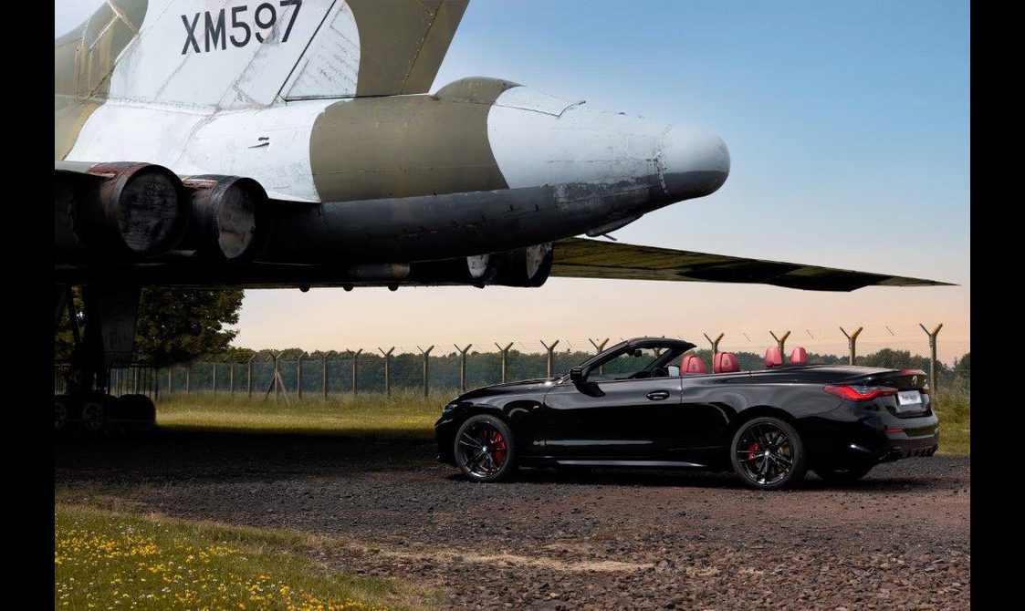 A black convertible car parked under the tail of a plane at the National Museum of Flight.