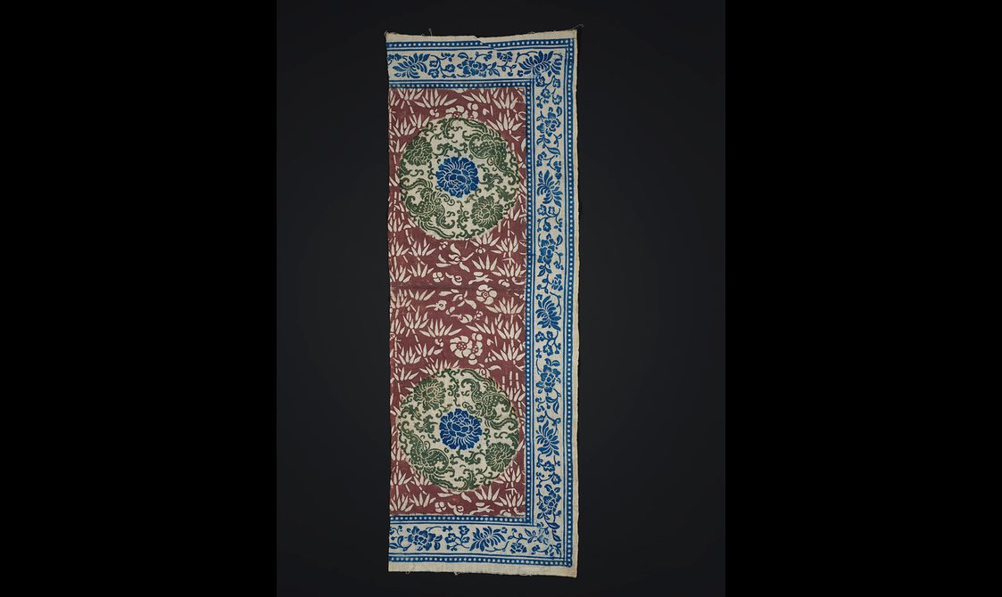 Sample of printed cotton with intricate red green and blue floral design.