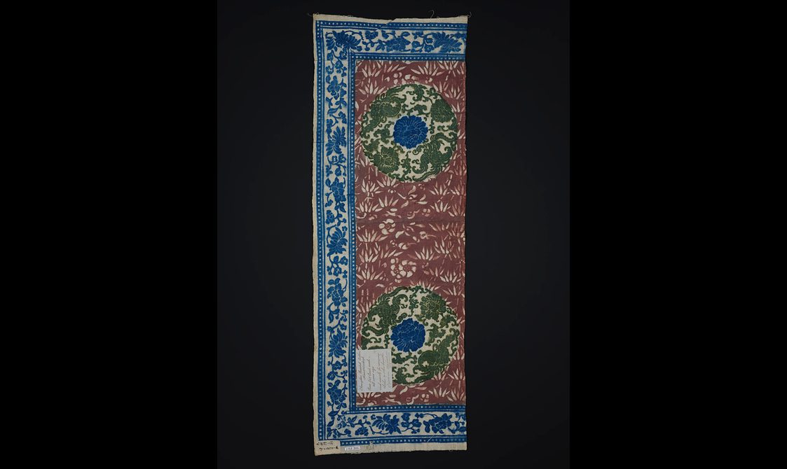 Printed sample of cotton featuring an intricate red green and blue floral design.