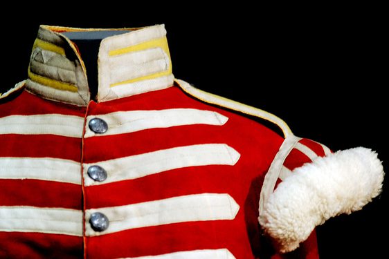 Shoulder of a red army uniform with white stripes and sleeve embellishments. The collar is yellow and white.