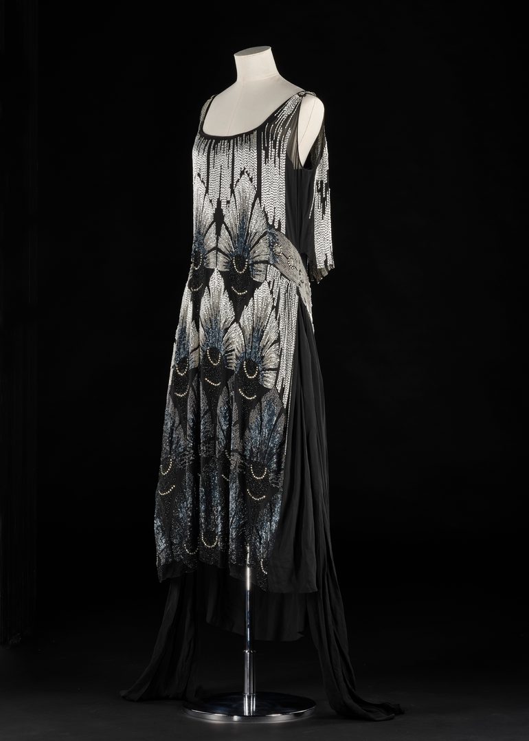 A dress model wearing a black dress with silver beading